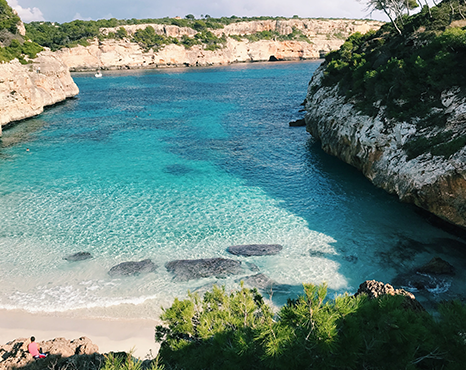 A calm cove with turquoise waters calmly lapping at a light sand beach